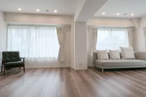 A wide view of JG Studio, where light streams in through two large windows. A sofa and chairs are arranged on either side of a central pillar.