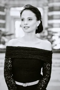 Black and white portrait of a woman in an off-the-shoulder lace dress against Tokyo architecture.