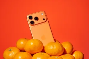 Orange smartphone resting on mikan oranges, a still-life product photo by JG in Tokyo.