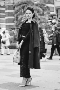 Elegant woman in a black lace dress with a coat over her shoulders posing in a Tokyo plaza, black and white editorial by JG.